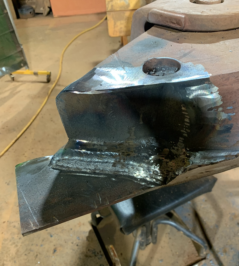 Precision MIG weld repair on heavy equipment component in the Cerberus workshop